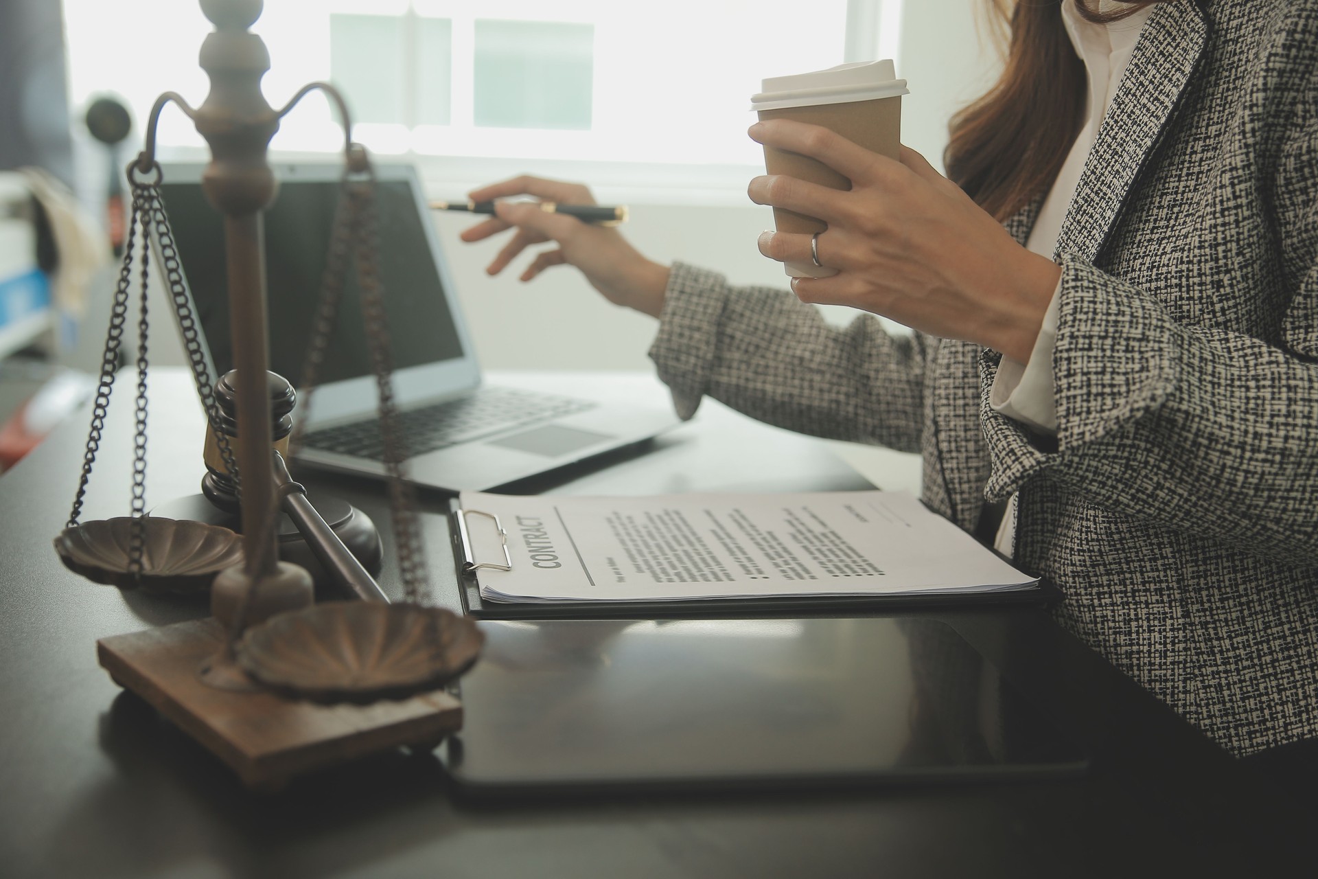 Afaceri și avocați discutând documente contractuale, cu o balanță din alamă pe birou, într-un birou. Imagine conceptuală despre drept, servicii juridice, consultanță, justiție și lege, cu efect de granulație cinematografică